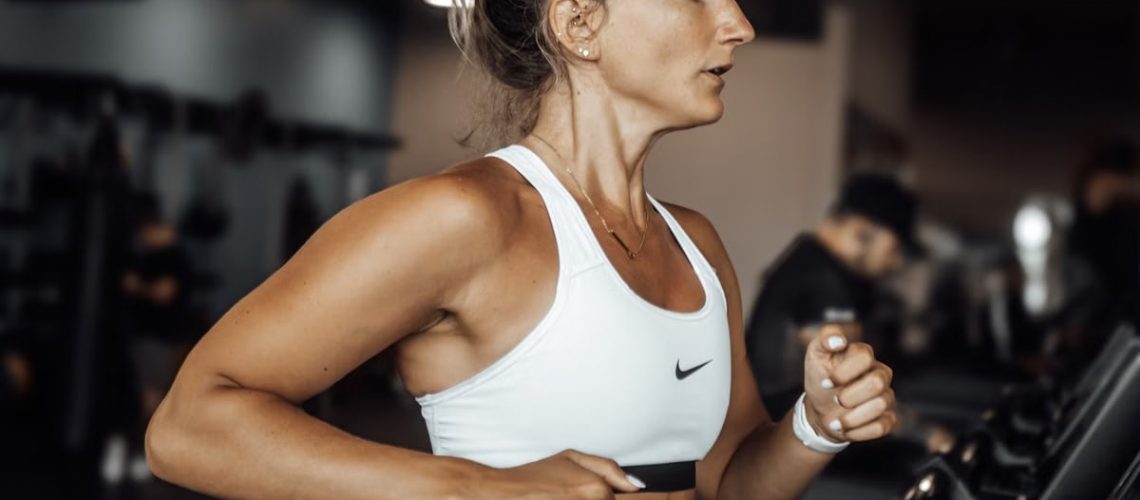 Fit woman exercising on a treadmill in a modern gym setting.